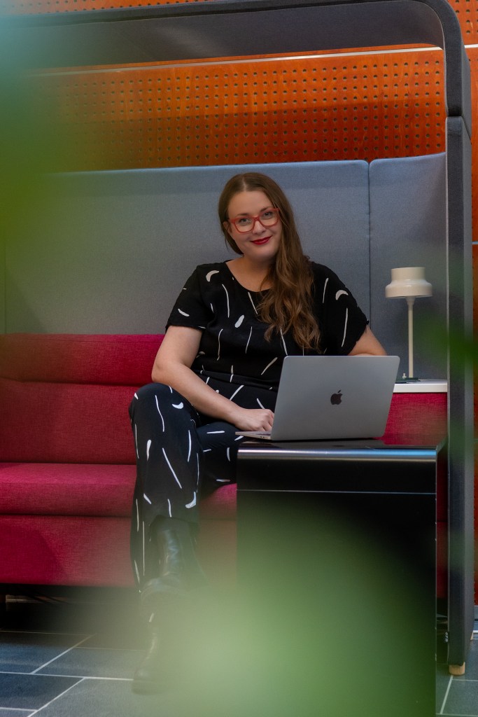 Nainen työskentelee kannettavalla tietokoneella modernissa toimistotilassa. Kuvassa Anu Karreinen, ulkoistettu markkinointipäällikkö